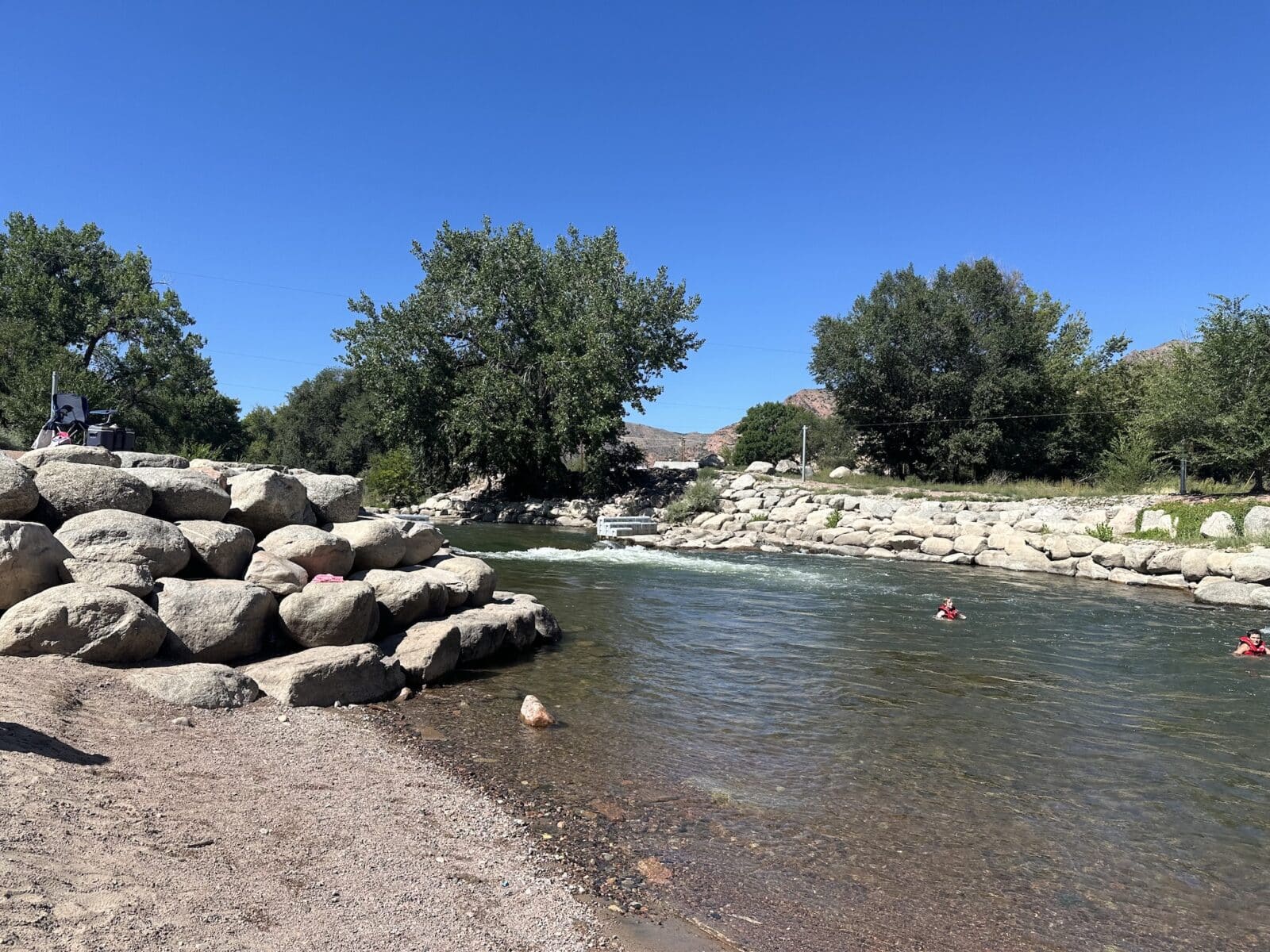 Two kids in life vests float in the Arkansas River in Canon City