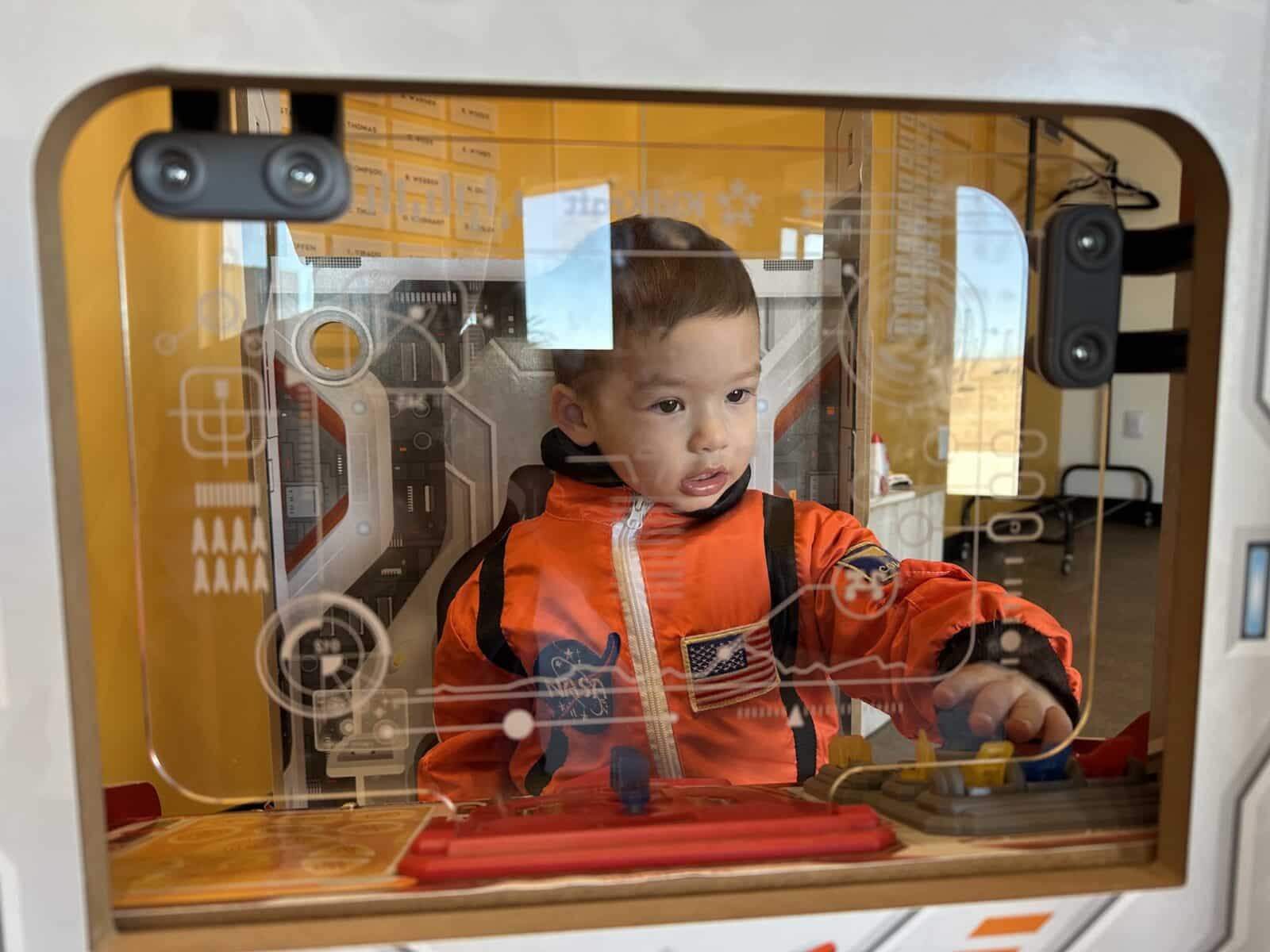 Boy plays in a spaceship arcade type game at Observer Ranch in Penrose, Colorado