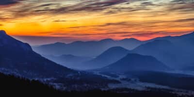 Yellow, orange and pink sky during sunrise over mountain silhouette in Rocky Mountain National Park