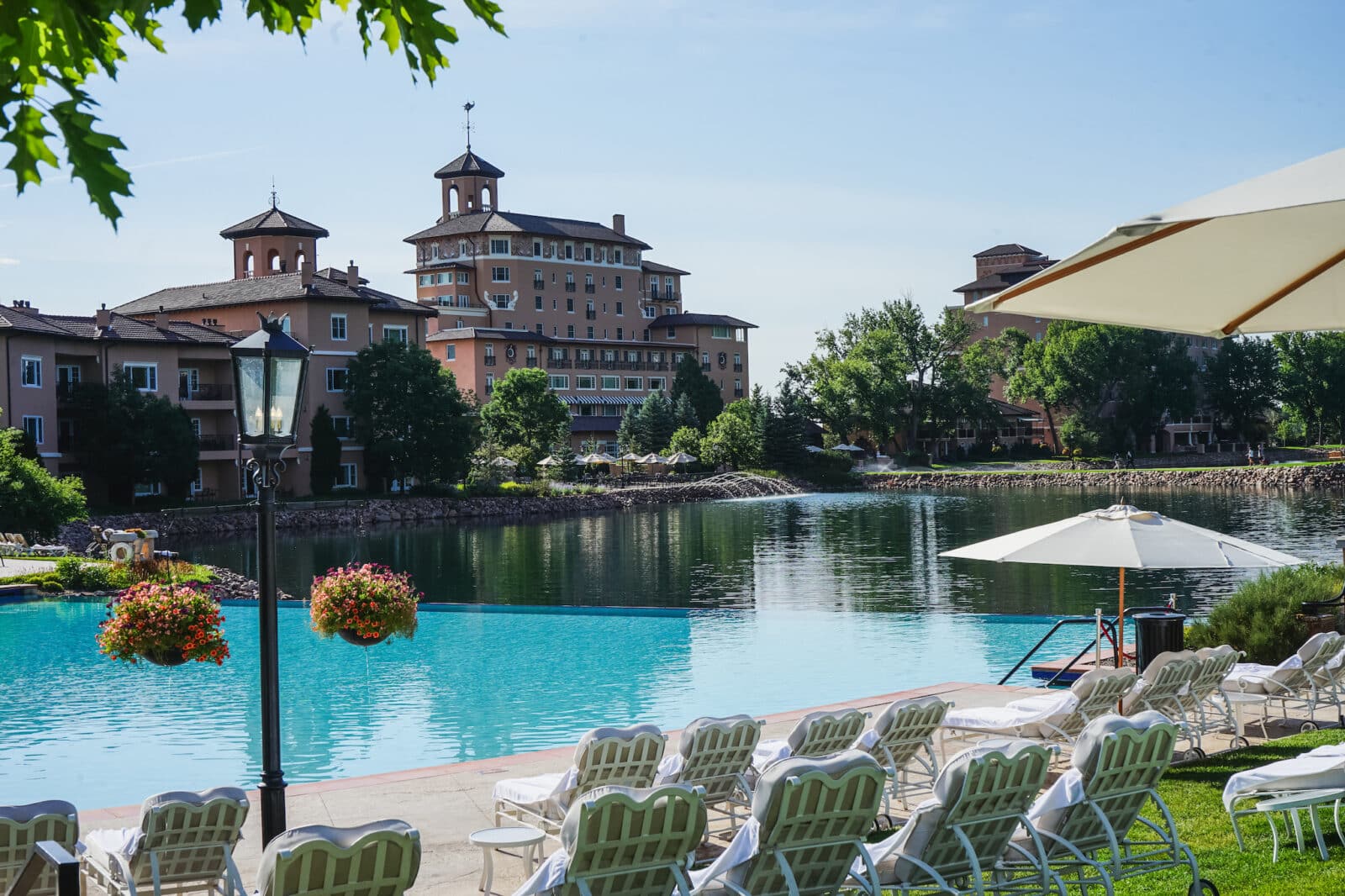 Chairs facing the large swimming pool with The Broadmoor hotel in distance